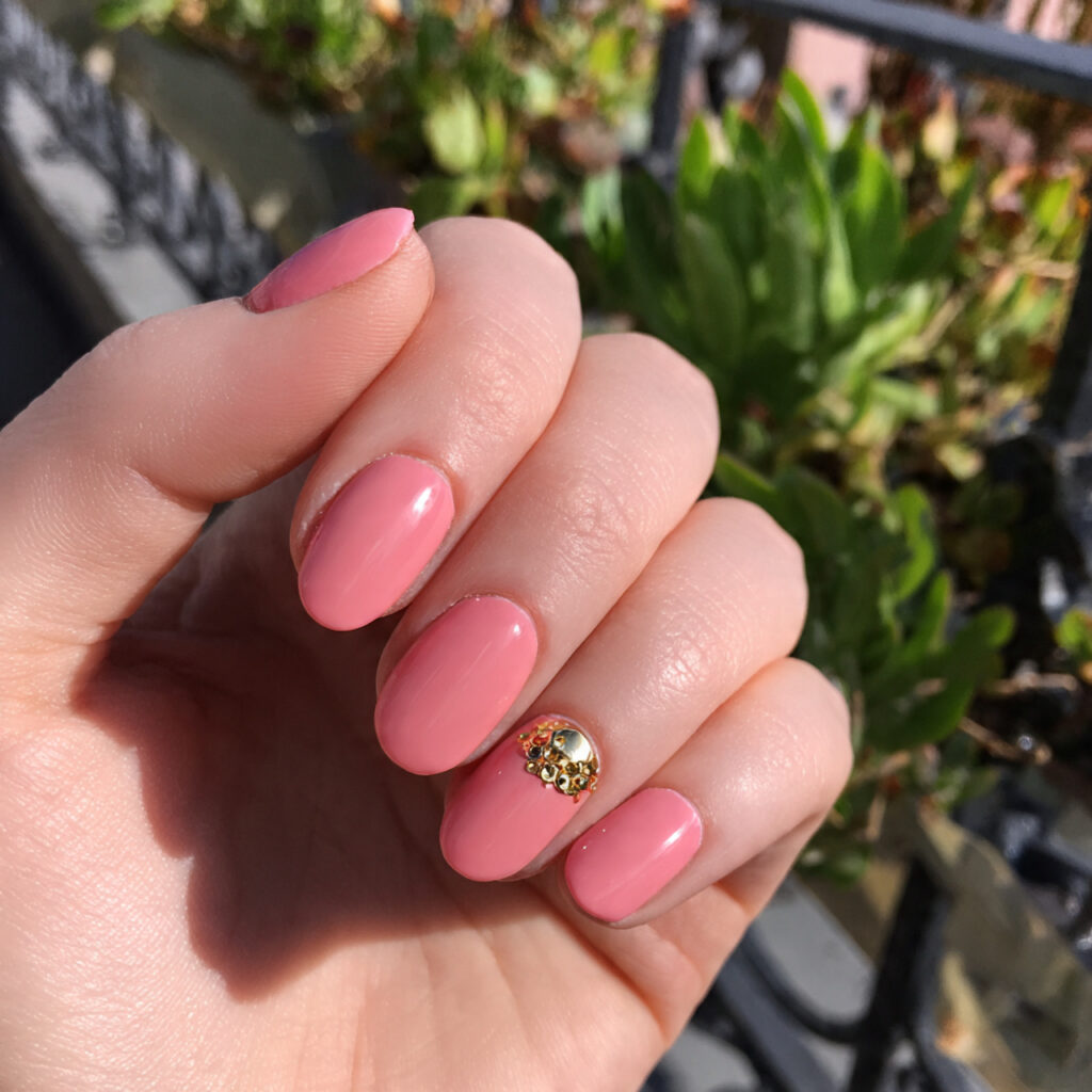 attractive peachy pink nails with gold charm with