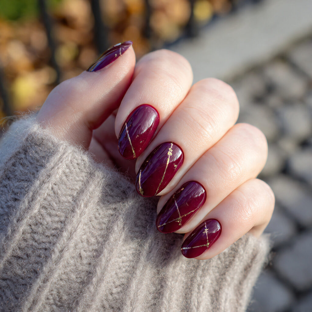 Red Nails With Gold: The Luxe, Glowing Combo You’ll Be Obsessed With 2 close up of a single hand with deep wine red nails