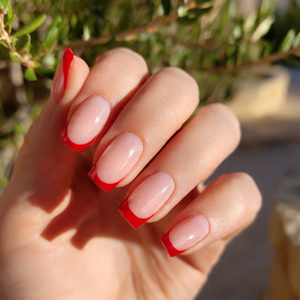 Red Quince Nails: Regal, Romantic & Made for Your Main Character Moment 10 close up of one hand with red french tip quince na 1