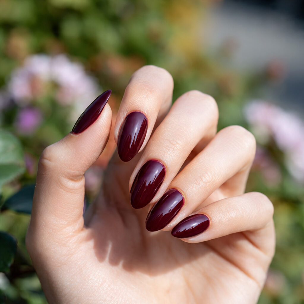one hand with attractive dark cherry almond nails